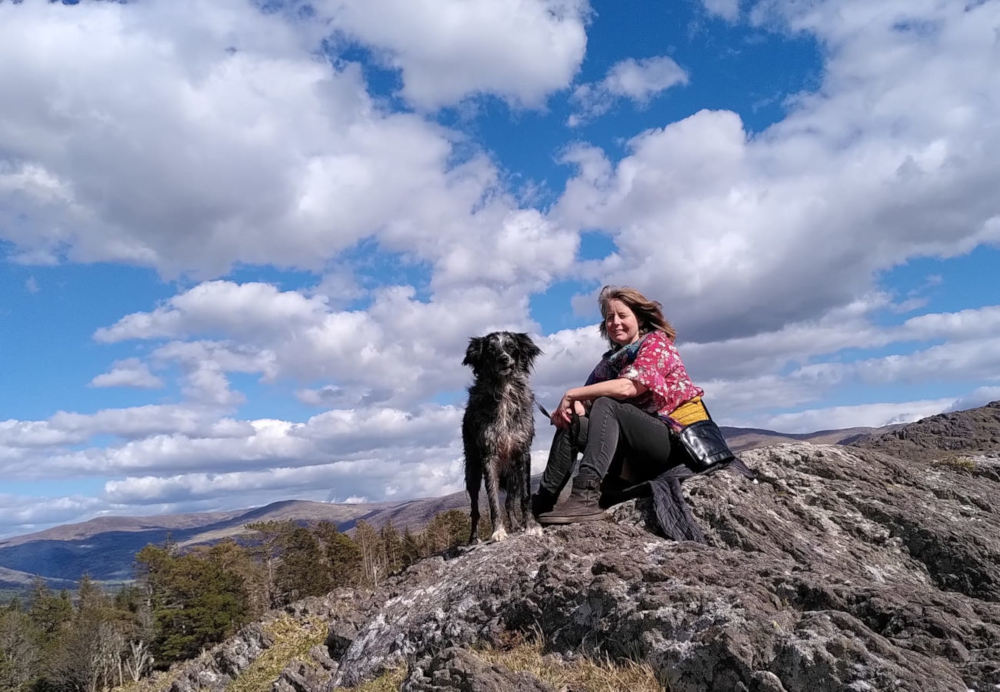 profile image of Claire Osborne sitting on a mountain with a dog