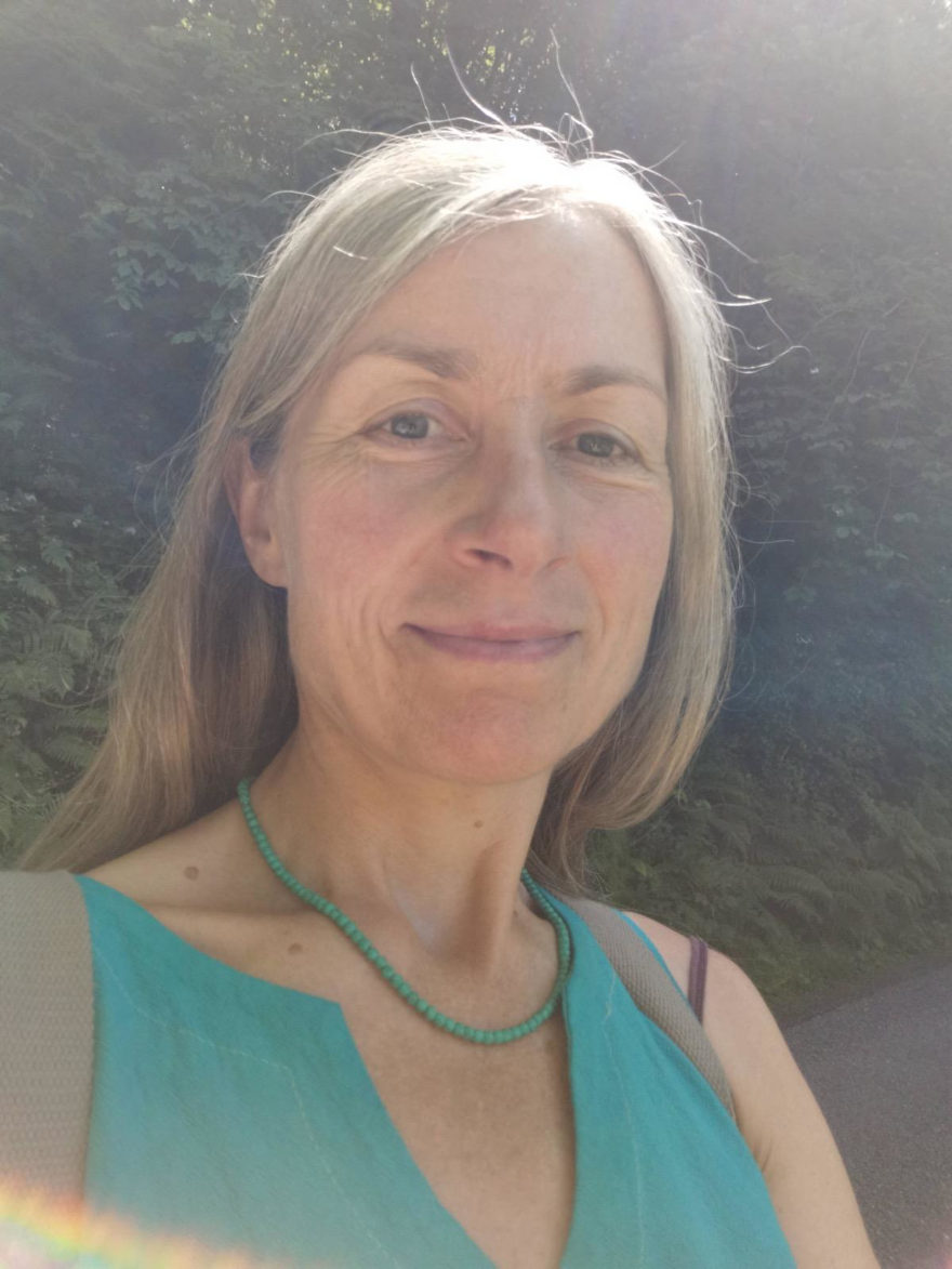 Photo of Fiona Walshe with hedgerows at her back and sun in her hair