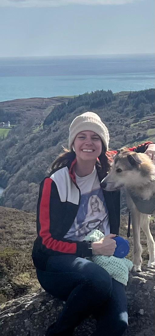 Liz Clark with a dog sitting on a boulder in the mountains