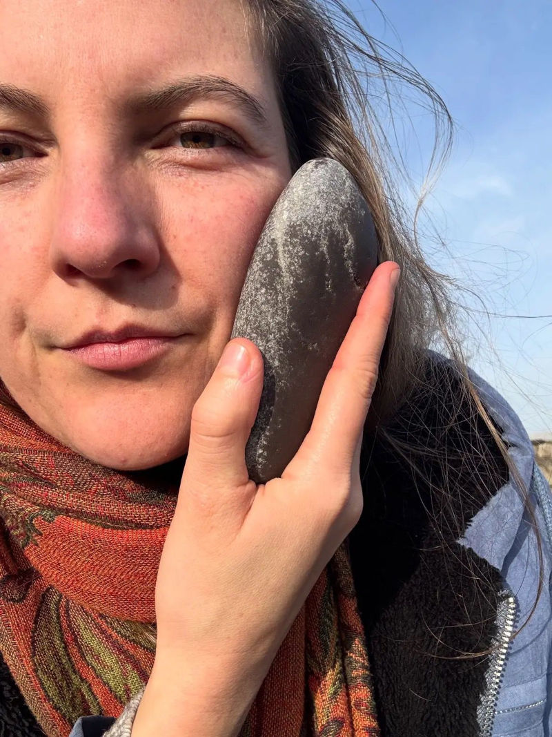 Sarah Louise with a holding a stone up to her face
